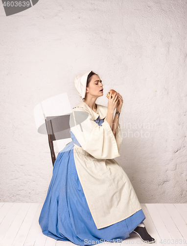 Image of Medieval Woman in Historical Costume Wearing Corset Dress and Bonnet.