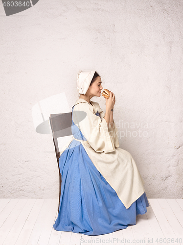 Image of Medieval Woman in Historical Costume Wearing Corset Dress and Bonnet.