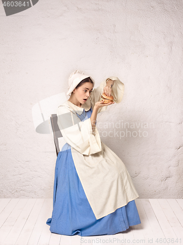 Image of Medieval Woman in Historical Costume Wearing Corset Dress and Bonnet.