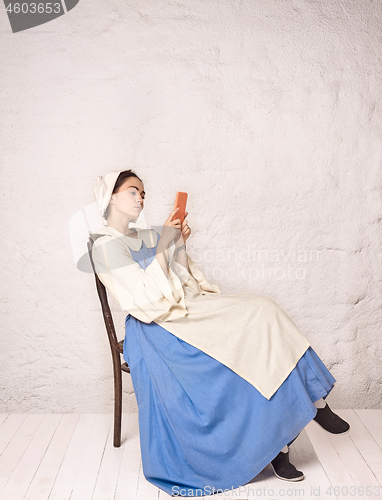 Image of Medieval Woman in Historical Costume Wearing Corset Dress and Bonnet.