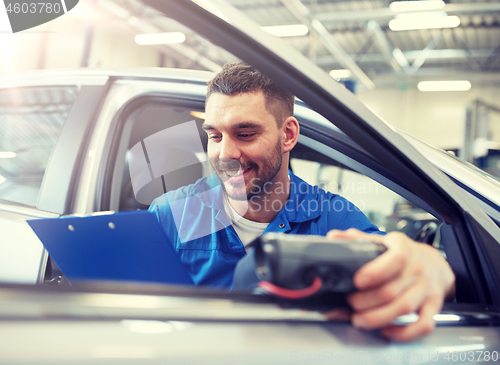 Image of mechanic man with diagnostic scanner at car shop