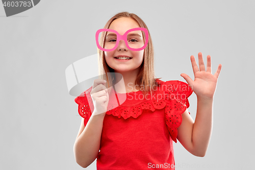 Image of smiling girl with big paper glasses waving hand