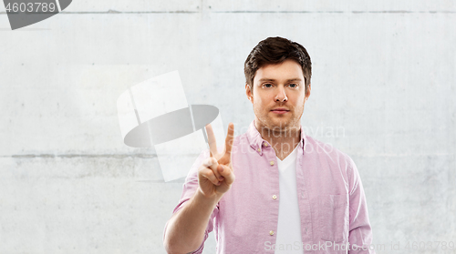 Image of young man showing two fingers over grey background