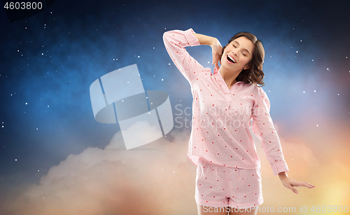 Image of happy woman in pajama stretching over night sky