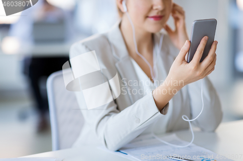 Image of businesswoman with earphones and smartphone