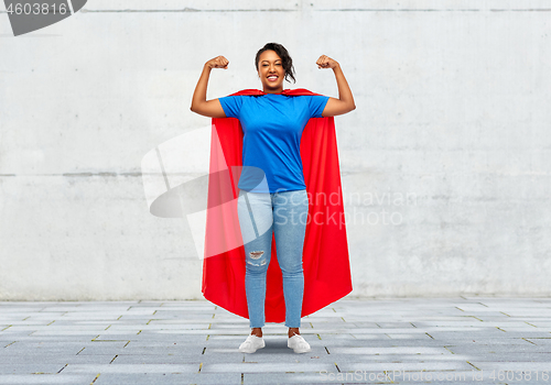 Image of happy african american woman in superhero red cape