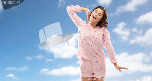 Image of happy young woman in pajama stretching over sky