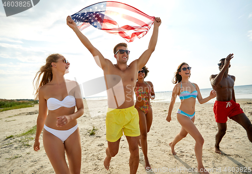 Image of happy friends with american flag on summer beach