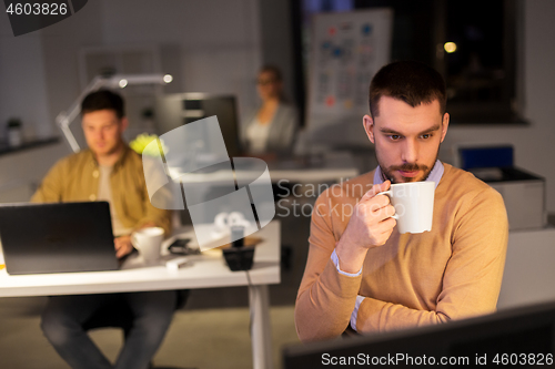 Image of happy male office worker drinking coffee