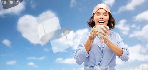 Image of woman in pajama and sleeping mask drinking coffee