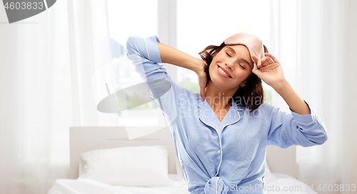 Image of happy young woman in pajama and eye sleeping mask