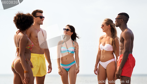 Image of happy friends hugging on summer beach