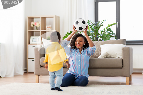 Image of mother and baby playing with soccer ball at home