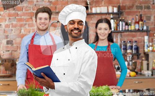 Image of male indian chef reading cookbook at cooking class