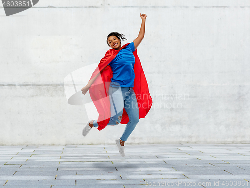 Image of happy african american woman in superhero red cape