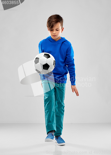 Image of smiling boy in blue hoodie playing soccer ball