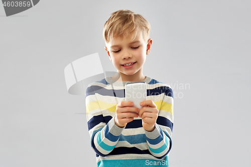 Image of little boy in striped pullover using smartphone