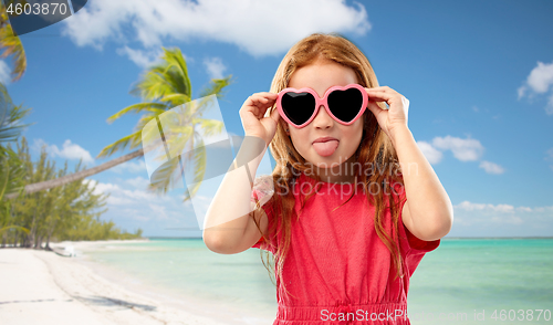 Image of redhead girl in heart shaped sunglasses on beach