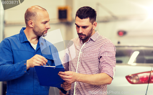 Image of auto mechanic with clipboard and man at car shop