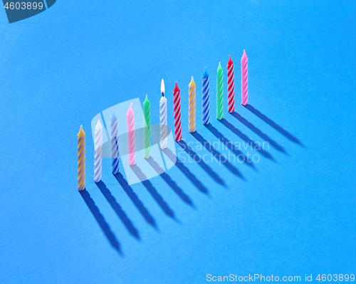 Image of Vertical standing candles for cake with shadows, one is burning.