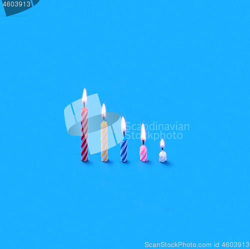 Image of Holiday burning multicolored candles of different height.