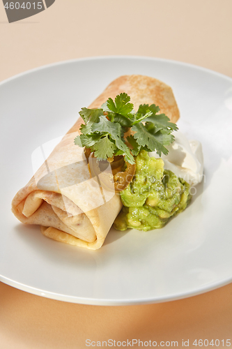 Image of Homemade pancake roll with spicy guacamole and white sauces.