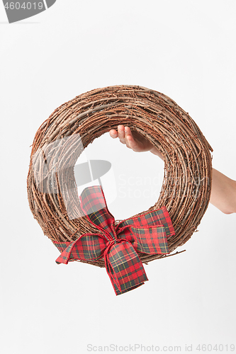 Image of Round wreath from dry twigs with bow in a woman hand.