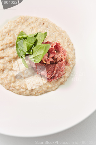 Image of Close-up view oatmeal porridge with lowfat ham and fresh spinach.