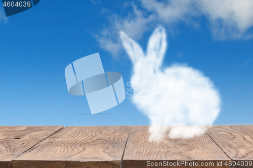 Image of Cloud Easter rabbit on a wooden table against blue sky background.