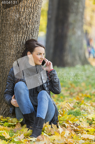 Image of Woman with a Mobile in a Forest in the Autumn