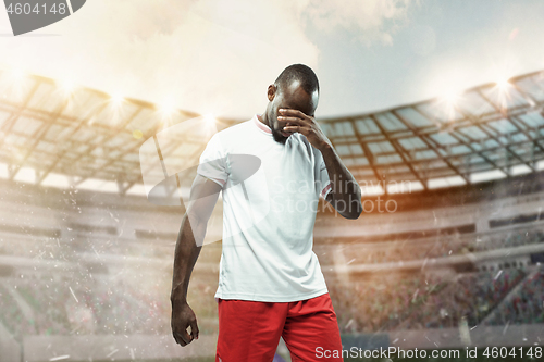 Image of The football player in motion on the field of stadium