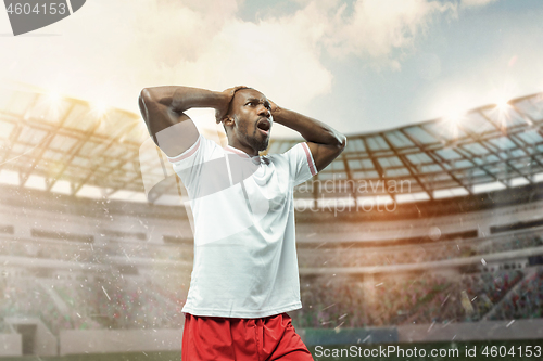 Image of The football player in motion on the field of stadium