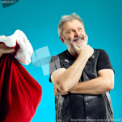 Image of An elderly man with white hair and beard and Christmas gift bag.