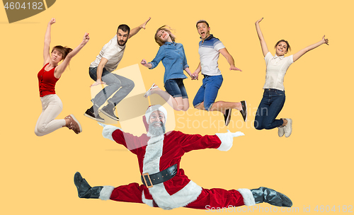 Image of Freedom in moving. young man and women jumping against yellow background