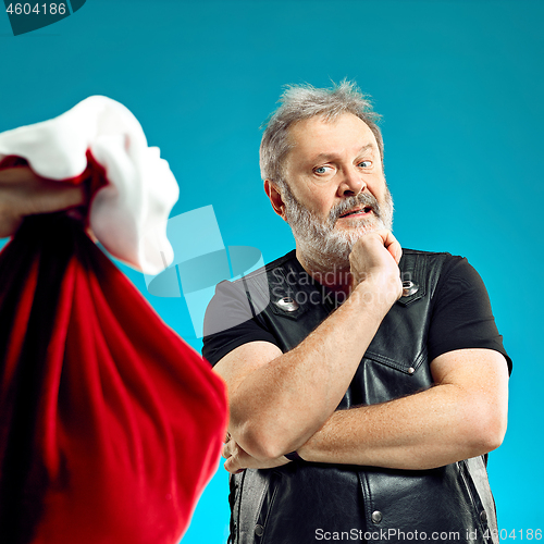 Image of An elderly man with white hair and beard and Christmas gift bag.