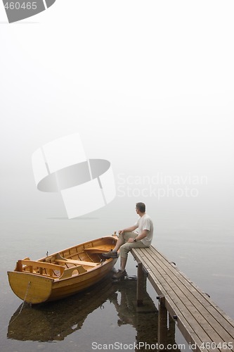 Image of Man at a lake on misty morning