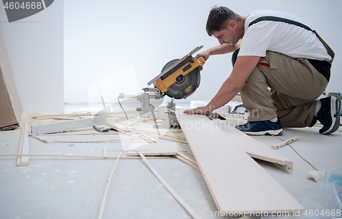 Image of Man cutting laminate floor plank with electrical circular saw