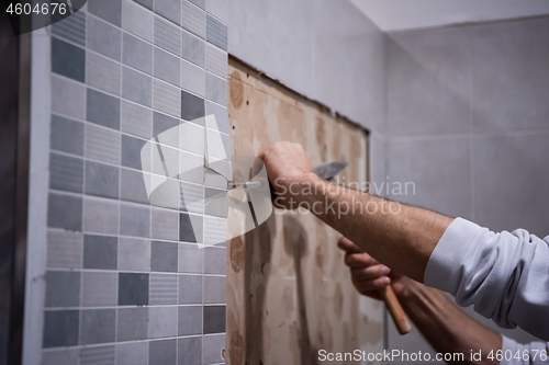 Image of worker remove demolish old tiles in a bathroom