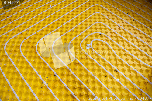 Image of yellow underfloor heating installation with white pipes