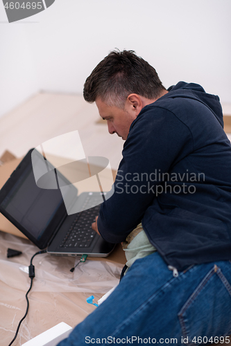 Image of man using laptop while lying on cardboard box