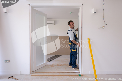 Image of carpenters installing glass door with a wooden frame