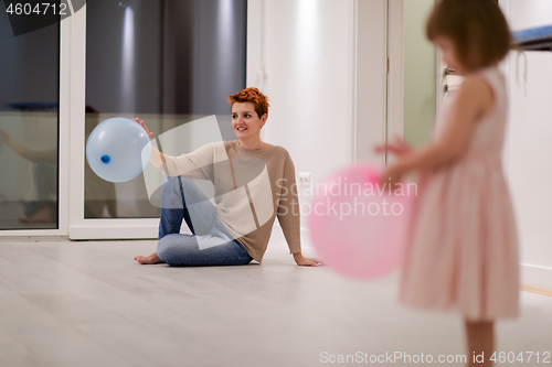 Image of mother and cute little daughter playing with balloons