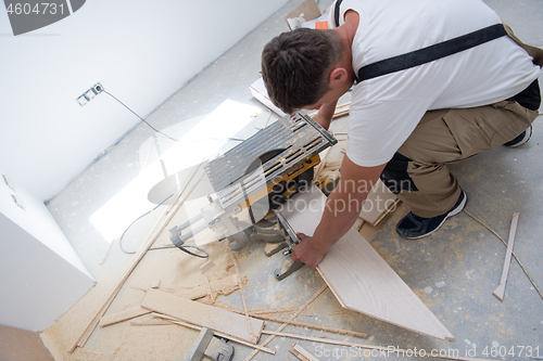 Image of Man cutting laminate floor plank with electrical circular saw