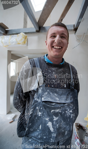 Image of portrait of construction worker with dirty uniform in apartment