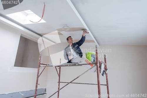 Image of construction worker plastering on gypsum ceiling