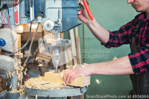 Image of Carpenters with electric drill machine drilling wooden board