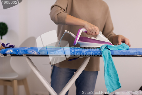 Image of Red haired woman ironing clothes at home