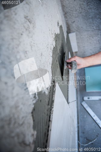 Image of worker installing big ceramic tiles