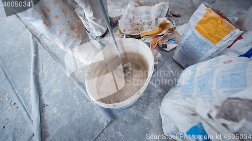 Image of construction worker mixing plaster in bucket