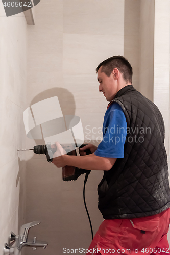 Image of construction worker drilling holes in the bathroom